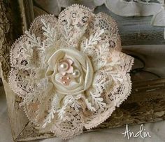 a close up of a flower on a piece of cloth with lace and pearls in the center