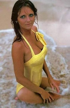 a woman in a yellow bathing suit sitting on the beach