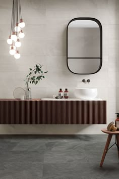 a bathroom with a sink, mirror and lights on the wall next to a stool