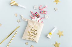 a bag filled with candy next to some gold and white straws on top of a blue surface