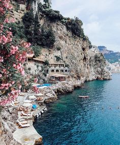 the beach is lined with umbrellas and lounge chairs on the cliff above the water