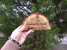 a person holding up a wooden sign that says nicole jones memorial at law in front of a tree