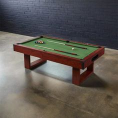 a pool table sitting in front of a brick wall