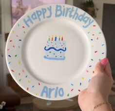 a person holding a plate with a birthday cake on it that says happy birthday arjo