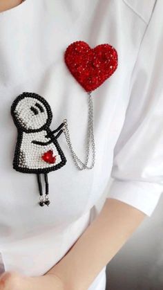 a woman wearing a white shirt with a red heart on it and a chain attached to her chest