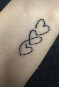 a small tattoo on the wrist of a woman with two hearts in each other's hands