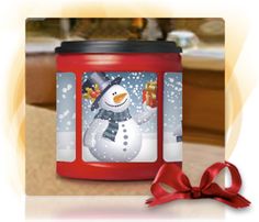 a red jar with a snowman on it and a bow around the lid is sitting on a table