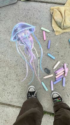 someone is standing on the sidewalk drawing with chalk and crayons