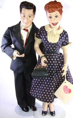 a man and woman doll standing next to each other holding purses in their hands