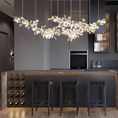 a modern kitchen with black cabinets and white flowers hanging from the chandelier over the island