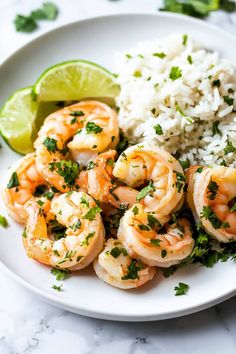 a white plate topped with shrimp and rice next to a lime wedge on top of a table