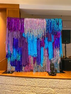 there is a large curtain made out of colorful streamers on the wall behind it