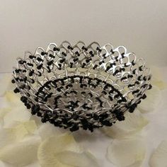 a metal bowl sitting on top of a white table covered in flowers and black beads