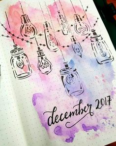 an open notebook with watercolors and ink on it that says december, surrounded by hanging mason jars