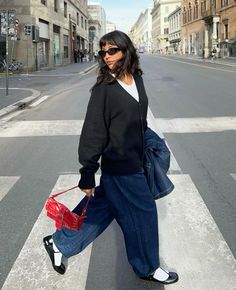 Spring layered outfit with a white tee, black cardigan, and dark blue jeans , wearing black ballerina flats and white socks with a pop of red purse walking photo spring aesthetic outfit style inspo 2024 it girl clean girl fashion Winter Flats Shoes Outfit, Winter Outfit Jeans Casual, Grandma Shoes Outfit, Black Fitted Tee Outfit, Dark Black Jeans Outfit, Flats And Socks Outfit, Ballerina Flat Outfits, Outfits With Rothy Clogs, Ballerina Flats With Socks