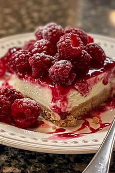 a piece of cheesecake topped with raspberries on a plate next to a fork