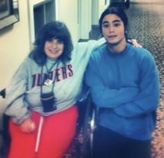 two people posing for the camera in a room with tile flooring and carpeted walls