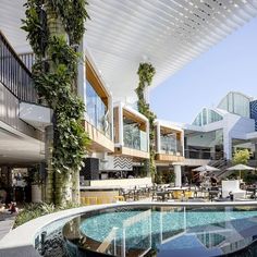 an indoor swimming pool surrounded by greenery and patio furniture in front of a modern building