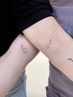 two people with matching tattoos on their arms, one has an elephant and the other has a giraffe