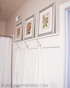 bathroom with towels hanging on the wall and three framed pictures above shower curtain rod holders