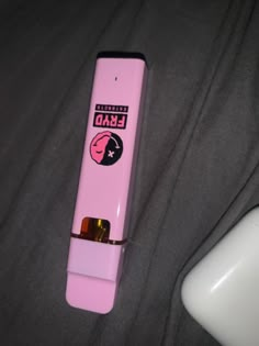 a pink electronic device sitting on top of a black bed next to a white lamp