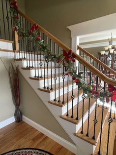 a staircase decorated for christmas with poinsettis and greenery on the railing