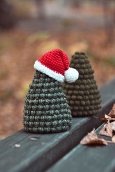 two knitted christmas trees sitting on top of a bench