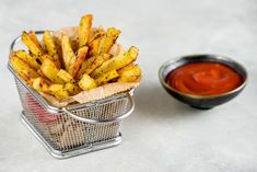 a basket filled with french fries next to a bowl of ketchup