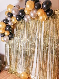 gold and black balloons are hanging from the ceiling