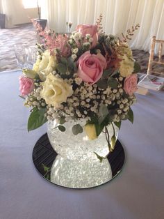 a vase filled with pink and white flowers on top of a blue table cloth covered table