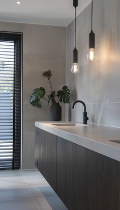 a kitchen area with a sink, counter top and two lights hanging from the ceiling