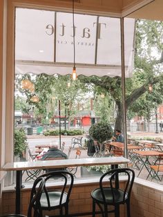 tables and chairs in front of a window with the word tattle on it's side