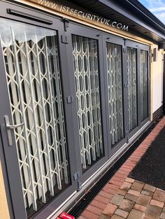 the side of a building with glass doors and brick walkway leading up to it's entrance