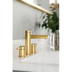 a gold faucet sits on a white countertop in front of a mirror