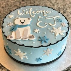 a blue cake decorated with snowflakes and a polar bear on the top that says welcome to us