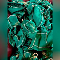 a pile of green scarves with gold lettering on them