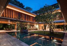 an indoor swimming pool in the middle of a large house with trees and lights around it