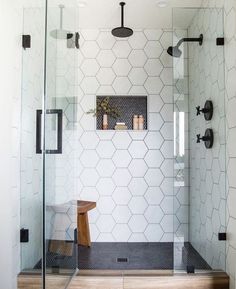 a bathroom with a glass shower door and wooden stool in front of the bathtub