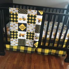 a baby crib bedding set with yellow and black construction trucks