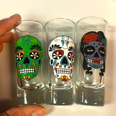 three shot glasses decorated with sugar skulls