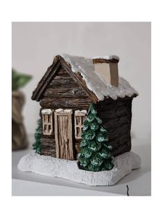 a small wooden house sitting on top of a snow covered ground next to a potted plant