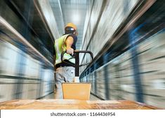 a man in a yellow safety vest is using a hand truck to move boxes through a warehouse