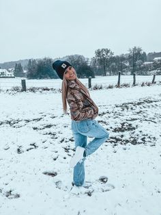 a woman is standing in the snow with her legs spread out and wearing blue jeans