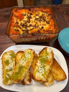 a plate with bread and green peppers on it next to a casserole dish