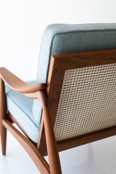 a wooden chair with blue upholstered seat and armrests sitting on a white floor