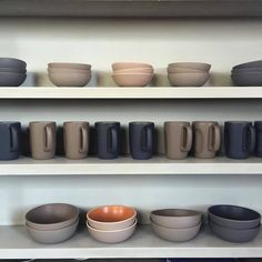 bowls and cups are lined up on shelves