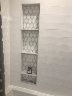 a bathroom with white tile and gray shower curtain in the bathtub, along with a black and white polka dot shower curtain