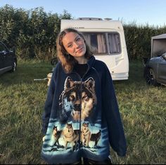 a woman standing in front of a camper with two wolfs on it's hoodie