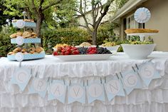 a table topped with lots of food next to a cake and cupcakes on top of it