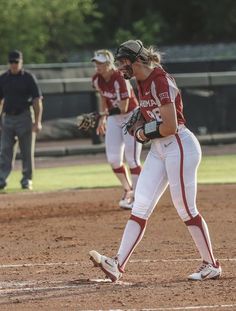 two softball players are standing on the field and one is holding her mitt up